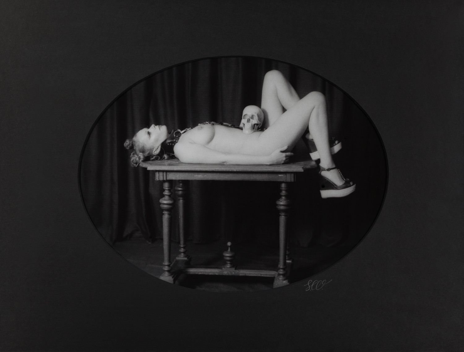 Olya Salomé VI by Johnny Welch. Photograph of a nude woman and a skull lying on a table