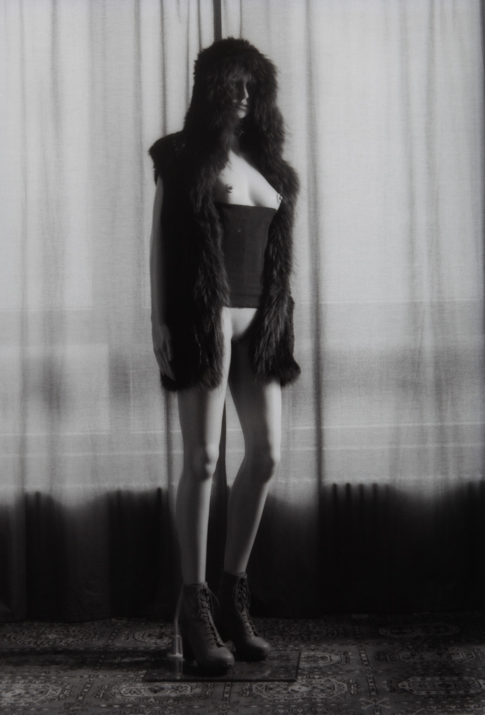 Mannequin Brat V by Johnny Welch. Photograph of a semi nude mannequin wearing a fur hood, boots, corset and leather choker.