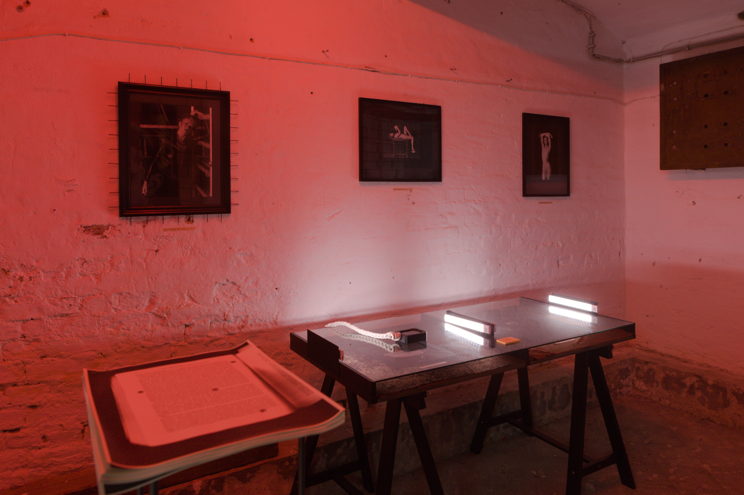 Installation view from photographic art exhibition at Pandora Art Gallery, Berlin, Germany. Three photographs mounted on the wall, two photographs displayed on a table under glass. 